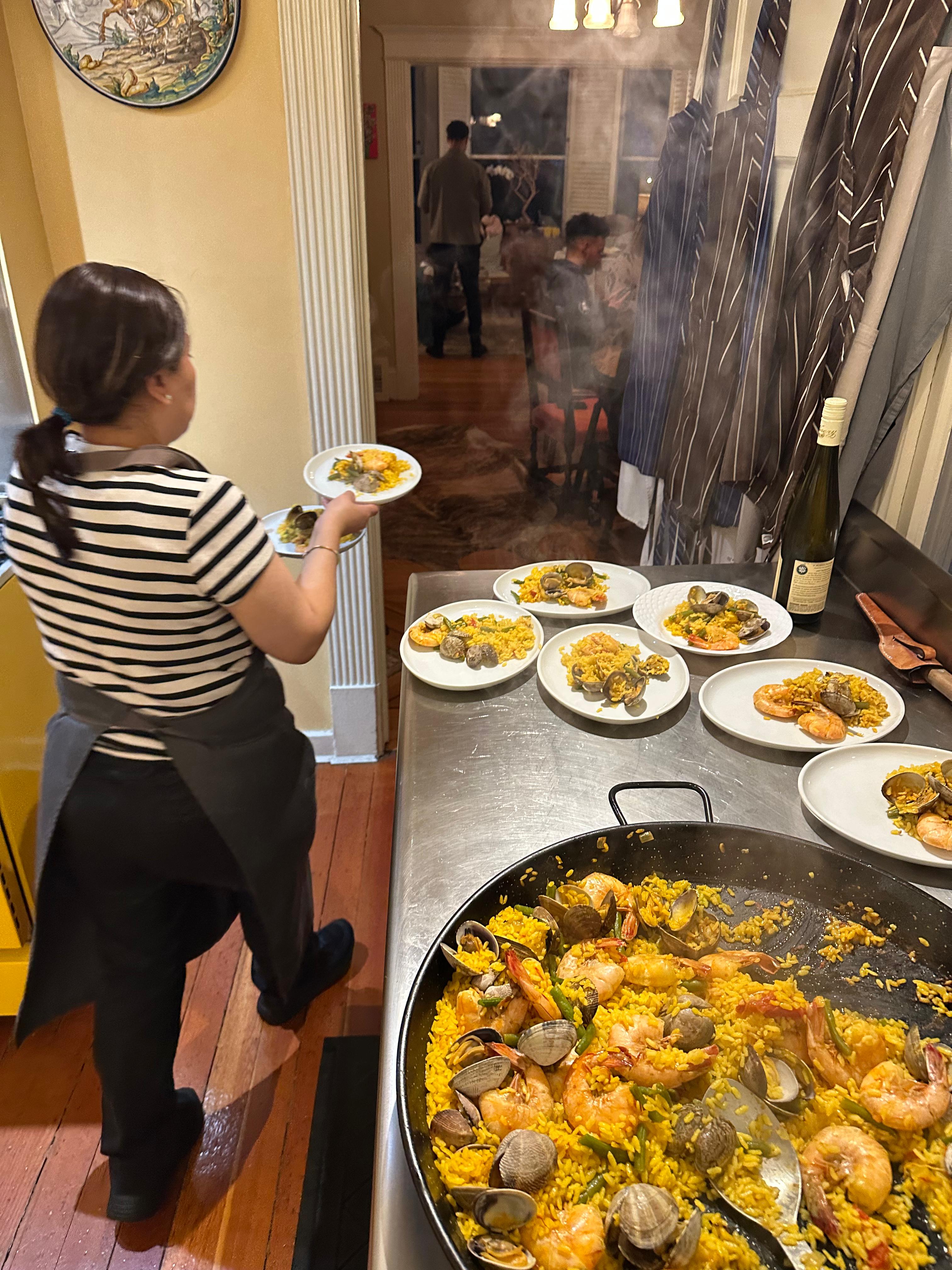 Claudia plating fresh paella during a CookWithJames cooking class in San Francisco