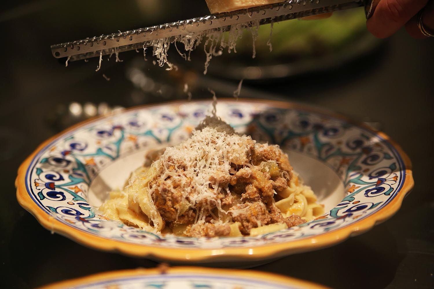 Fresh Parmigiano Reggiano grated over handmade pasta on an Italian ceramic plate — CookWithJames