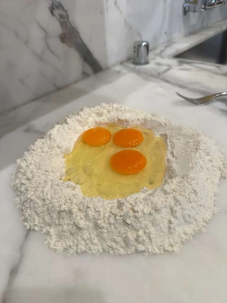 Flour well with golden egg yolks ready for hand-made pasta dough
