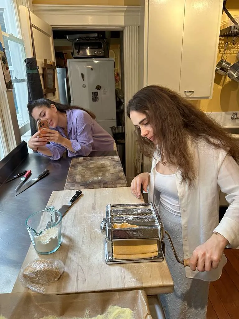 Guest rolling fresh pasta dough through a hand-crank pasta machine